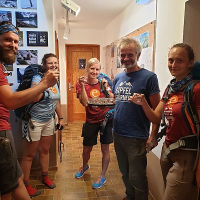Das ist ein außergewöhnlicher Empfang. Hüttenwart Thomas empfängt unsere Crew auf der Ravensburger Hütte im Gipfelstürmer-Shirt mit einer Runde Schnaps.